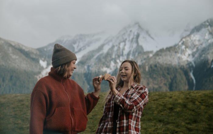 Two girls toasting their smores, with mountains in the background