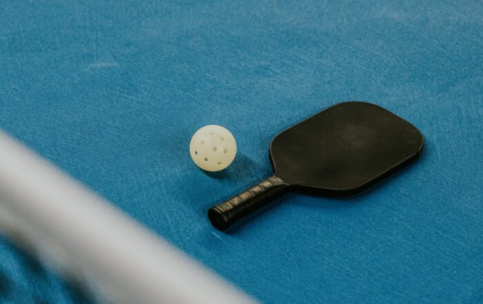 A pickleball racquet and ball on the floor of a court