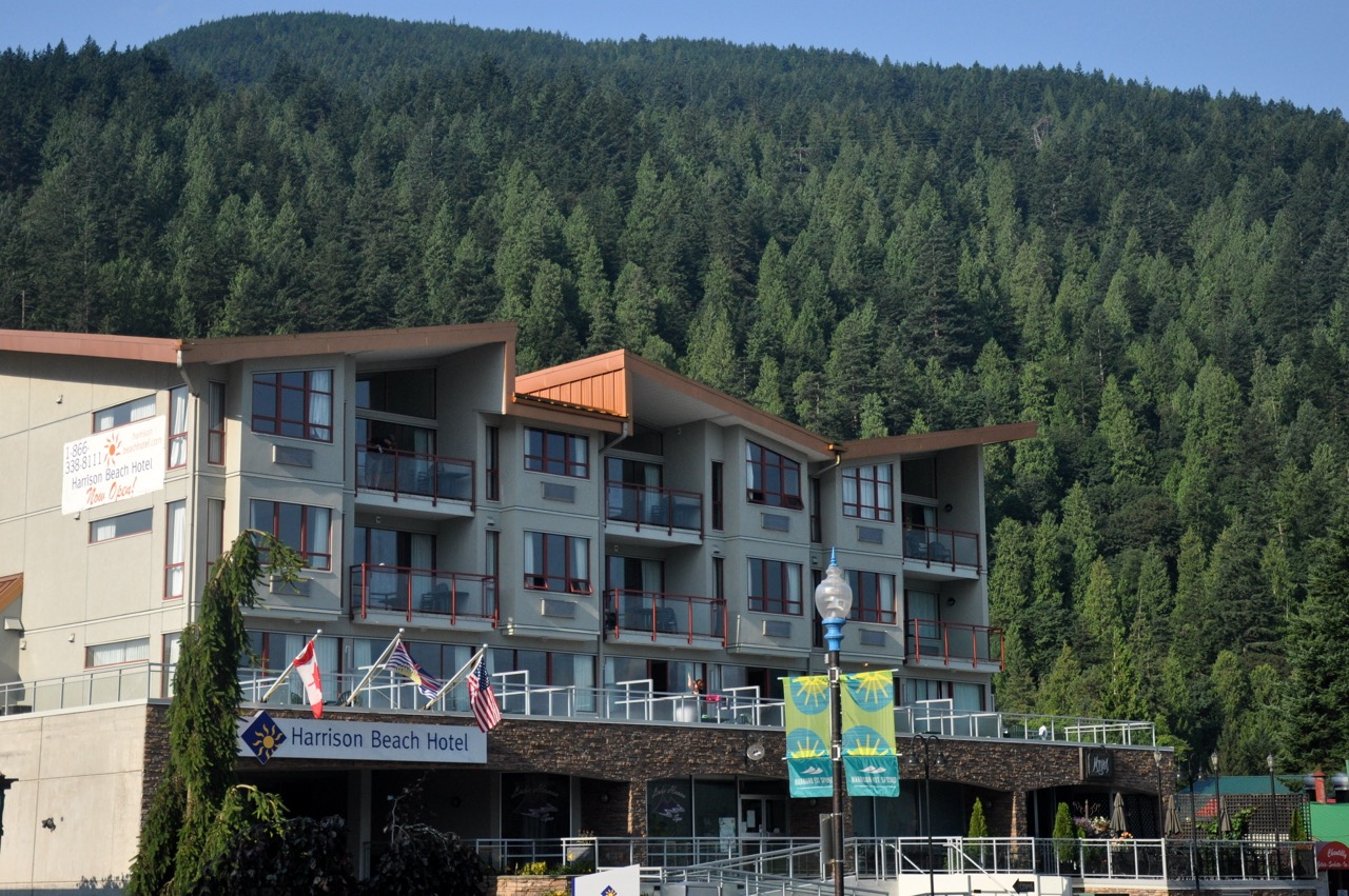 A large hotel with a forest mountain behind it
