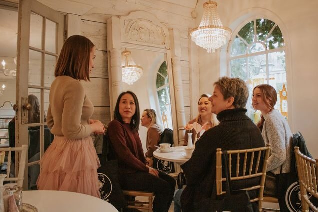 A person takes the order of people sitting at a table inside a high tea restaurant.