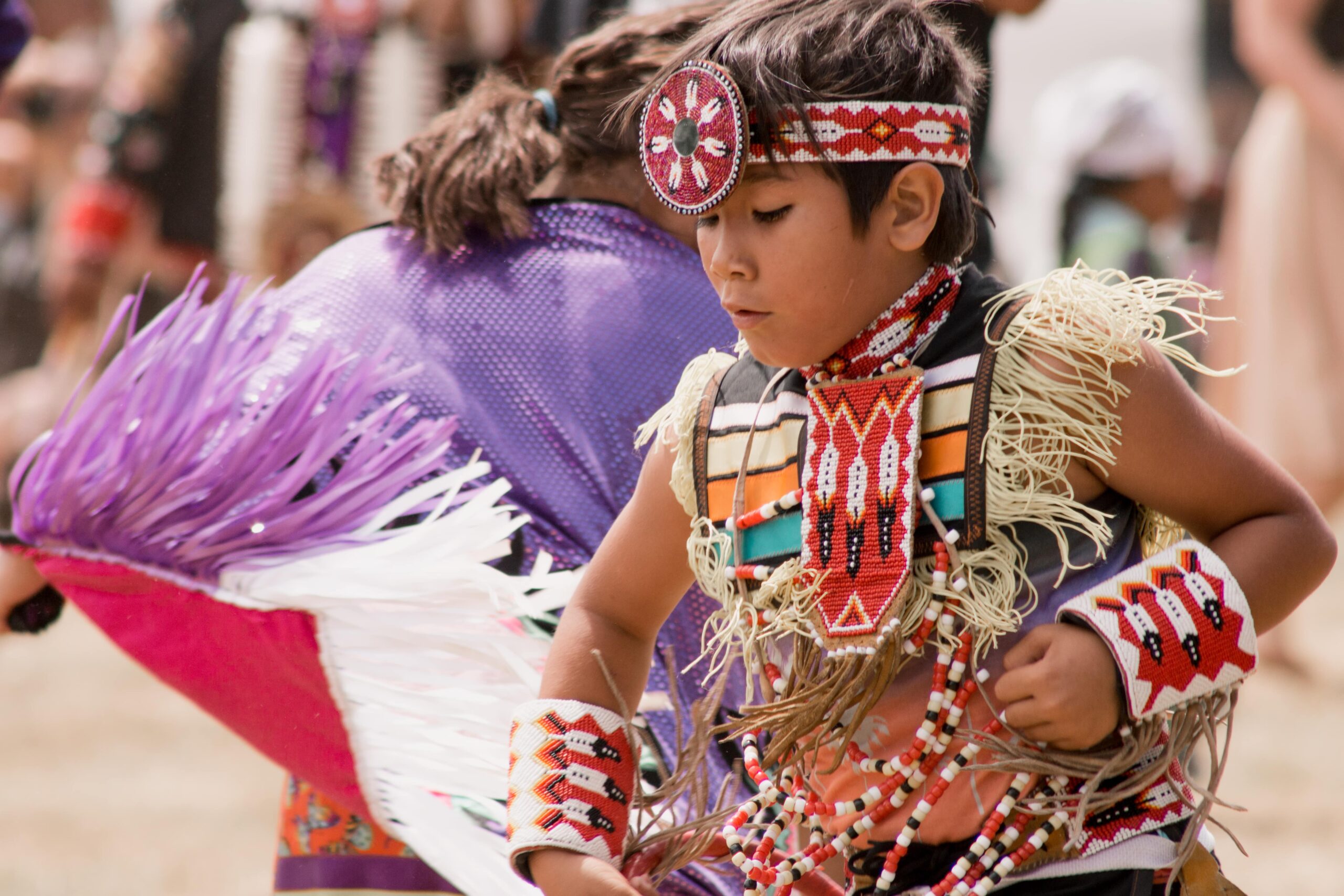 A young child dressed in Indigenous regalia takes part in a performance.