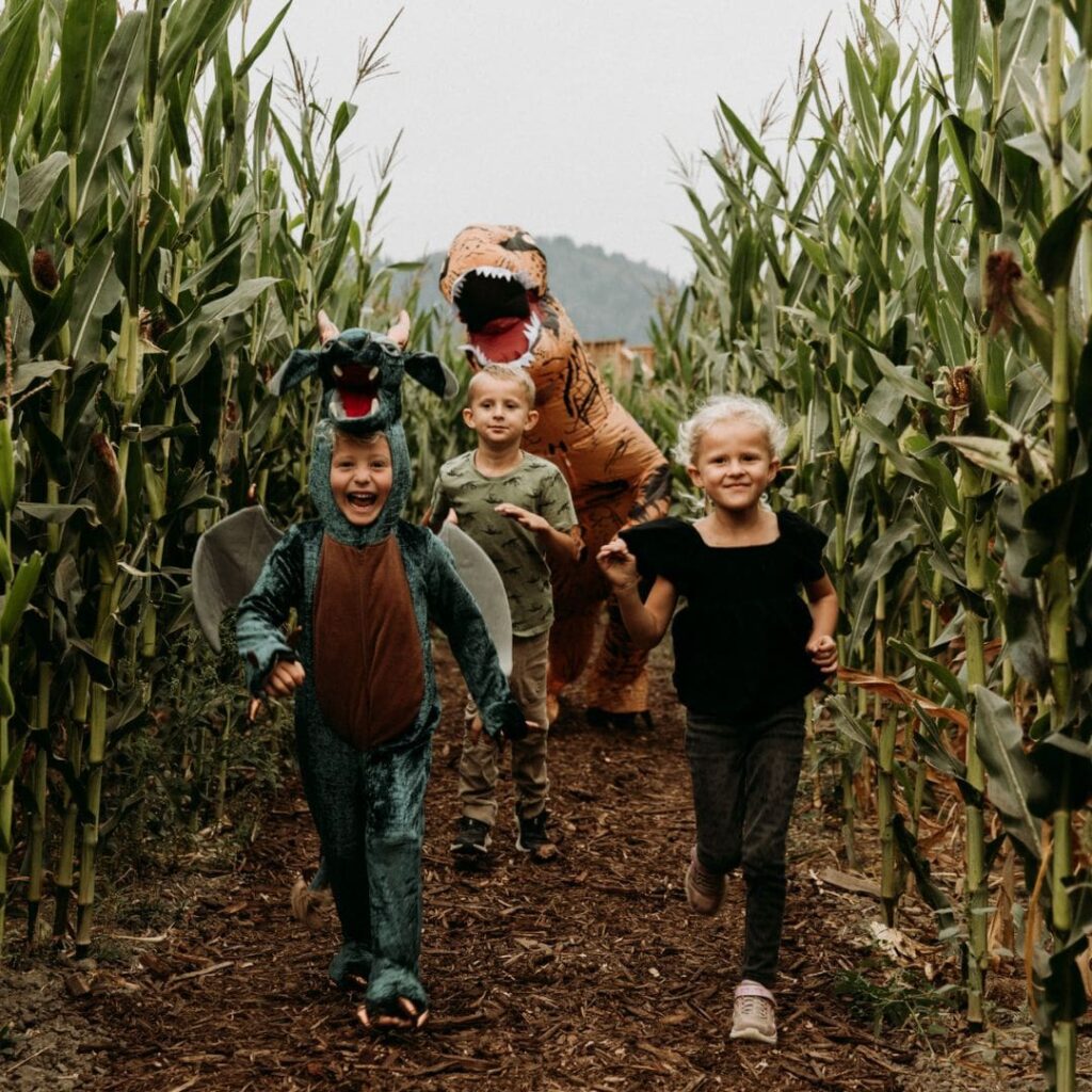 children in costumes run in maze